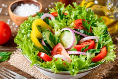 Ahşap masa üzerinde yeşillikleri ile taze sebze salatası.