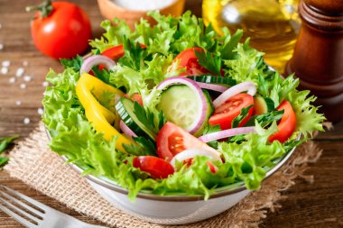 Ahşap masa üzerinde yeşillikleri ile taze sebze salatası.