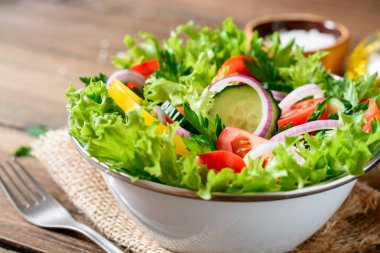 Ahşap masa üzerinde yeşillikleri ile taze sebze salatası.