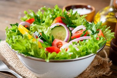 Ahşap masa üzerinde yeşillikleri ile taze sebze salatası.