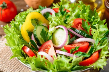 Ahşap masa üzerinde yeşillikleri ile taze sebze salatası.