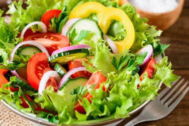 Ahşap masa üzerinde yeşillikleri ile taze sebze salatası.
