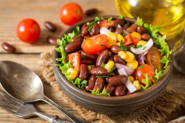 Fasulye ahşap masa üzerinde seramik kase taze sebze salatası.