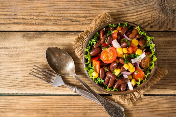 Ensalada de verduras frescas con frijoles en tazón de cerámica sobre mesa de madera . —  Fotos de Stock