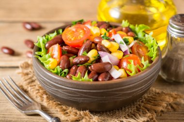 Fasulye ahşap masa üzerinde seramik kase taze sebze salatası.
