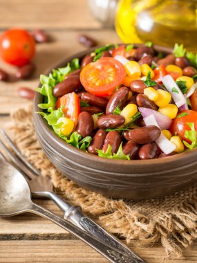 Fasulye ahşap masa üzerinde seramik kase taze sebze salatası.