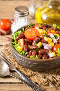 Fasulye ahşap masa üzerinde seramik kase taze sebze salatası.
