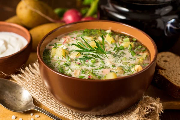 Okroshka. Traditional Russian summer cold soup with sausage, vegetables and kvass in bowl on wooden background. — Stock Photo, Image