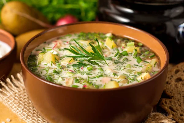 Okroshka. Traditional Russian summer cold soup with sausage, vegetables and kvass in bowl on wooden background. — Stock Photo, Image