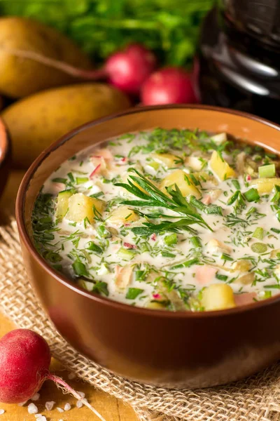 Okroshka. Traditional Russian summer cold soup with sausage, vegetables and kvass in bowl on wooden background. — Stock Photo, Image