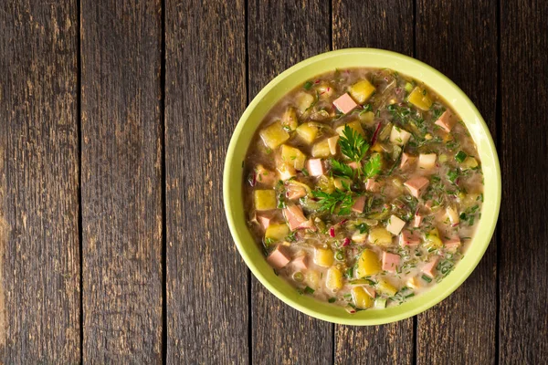 Okroshka. Traditional Russian summer cold soup with sausage, vegetables and kvass in bowl on wooden background. — Stock Photo, Image