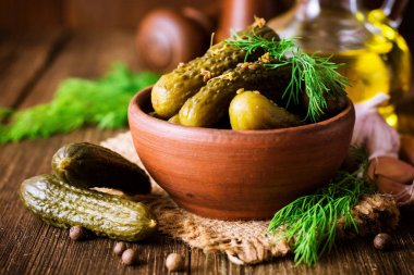 Karanlık rustik ahşap masa üzerinde seramik kase dereotu salatalık turşusu.