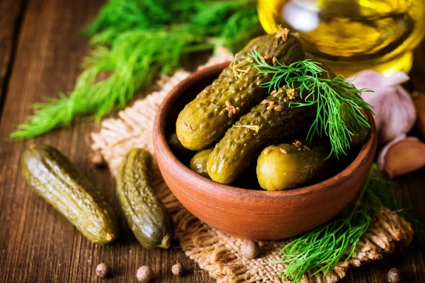 Pickled cucumbers with dill in ceramic bowl on dark rustic wooden table. — Stock Photo, Image