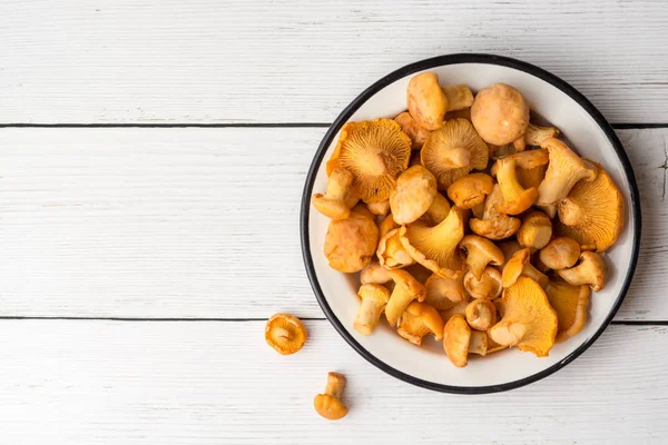 Beyaz ahşap zemin üzerinde plaka ham mantar Cantharellus cibarius.