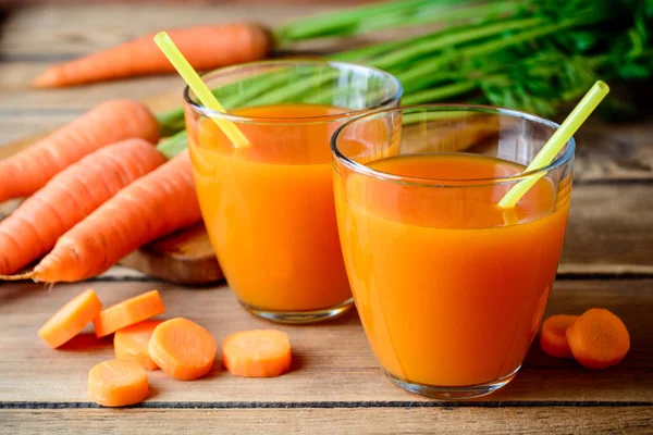 Succo di carota fresco in bicchieri su tavolo di legno rustico . — Foto Stock