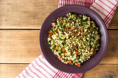 Bulgur, domates, maydanoz, yeşil soğan ve nane plaka üzerinde ahşap masa Tabbouleh salatası.