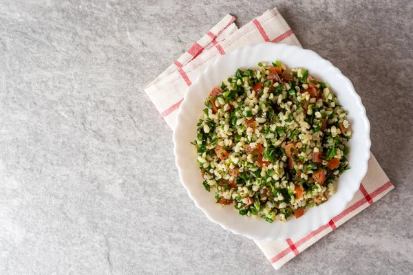 Bulgur, domates, maydanoz, yeşil soğan ve nane plaka gri taş masada Tabbouleh salatası.