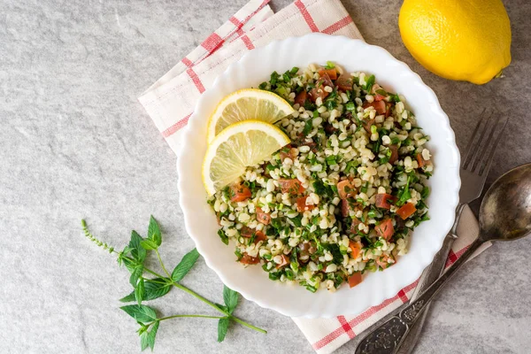 Bulgur, domates, maydanoz, yeşil soğan ve nane plaka gri taş masada Tabbouleh salatası.