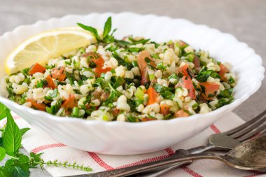 Bulgur, domates, maydanoz, yeşil soğan ve nane plaka gri taş masada Tabbouleh salatası.