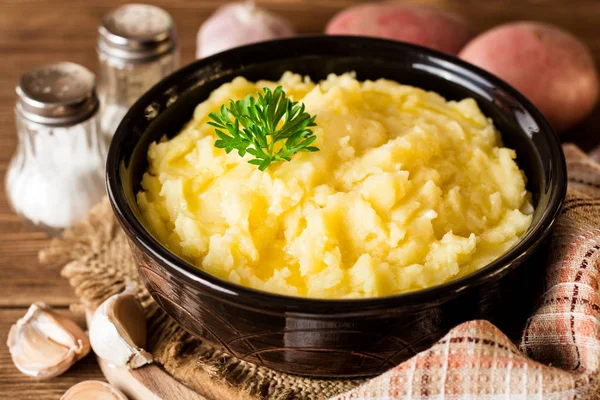 Purê de batatas com manteiga e salsa fresca na tigela em mesa de madeira rústica — Fotografia de Stock