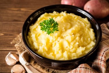 Tereyağı ve rustik ahşap masa üzerinde kase taze maydanoz ile patates püresi