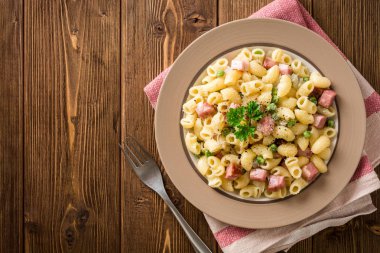 Yeşil bezelye, soğan, pastırma ve ahşap zemin üzerine peynir ile makarna