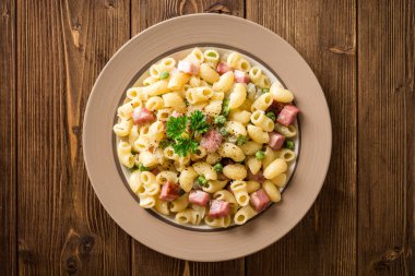 Yeşil bezelye, soğan, pastırma ve ahşap zemin üzerine peynir ile makarna