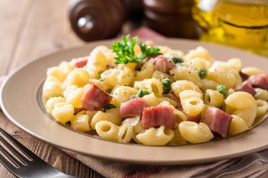 Yeşil bezelye, soğan, pastırma ve ahşap zemin üzerine peynir ile makarna