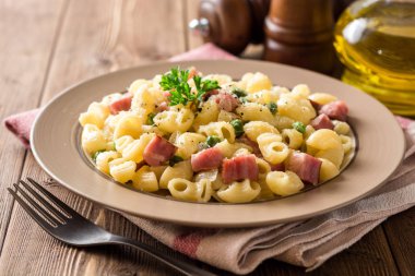 Yeşil bezelye, soğan, pastırma ve ahşap zemin üzerine peynir ile makarna