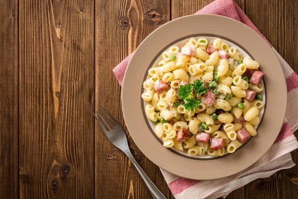 Yeşil bezelye, soğan, pastırma ve ahşap zemin üzerine peynir ile makarna