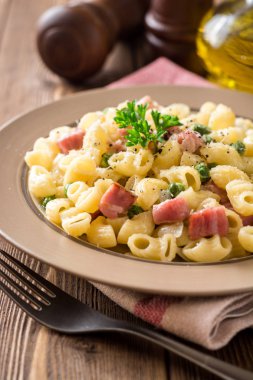 Yeşil bezelye, soğan, pastırma ve ahşap zemin üzerine peynir ile makarna