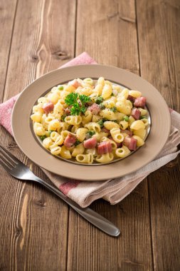 Yeşil bezelye, soğan, pastırma ve ahşap zemin üzerine peynir ile makarna