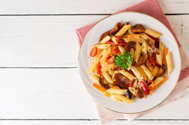 Mantar, biber, biber ve maydanoz Beyaz ahşap zemin üzerinde beyaz tabakta Penne makarna.