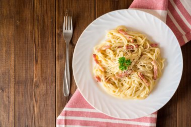 Klasik makarna carbonara. Spagetti ile pastırma, yumurta sarısı ve parmesan peyniri koyu ahşap arka plan üzerinde beyaz tabakta Yumurta.