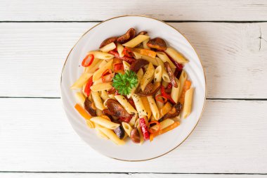 Mantar, biber, biber ve maydanoz Beyaz ahşap zemin üzerinde beyaz tabakta Penne makarna.