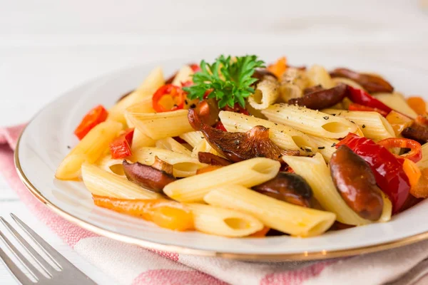 Mantar, biber, biber ve maydanoz Beyaz ahşap zemin üzerinde beyaz tabakta Penne makarna.