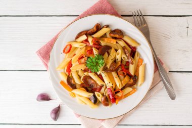 Mantar, biber, biber ve maydanoz Beyaz ahşap zemin üzerinde beyaz tabakta Penne makarna.