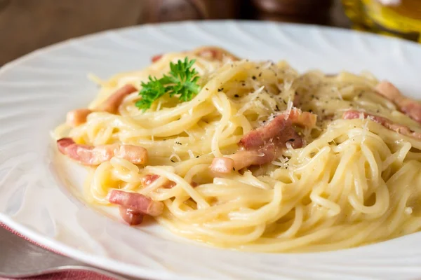 Klasyczny makaron carbonara. Spaghetti z boczkiem, jajko żółtka i parmezanem ser na białym talerzu na ciemnym tle drewnianych. — Zdjęcie stockowe