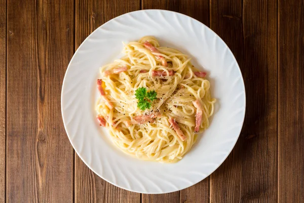 Klasik makarna carbonara. Spagetti ile pastırma, yumurta sarısı ve parmesan peyniri koyu ahşap arka plan üzerinde beyaz tabakta Yumurta.