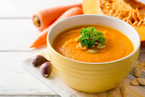 Κολοκύθι και καρότο σούπα με σπόρους κολοκύθας και μαϊντανό σε μπολ σε άσπρο φόντο ξύλινη κρέμα. — Φωτογραφία Αρχείου