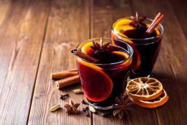 İki bardak Noel şarabı portakallı ve ahşap arka planda baharatlı..