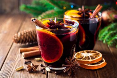 İki bardak Noel şarabı portakallı ve ahşap arka planda baharatlı..