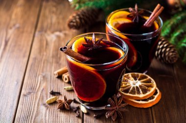 İki bardak Noel şarabı portakallı ve ahşap arka planda baharatlı..