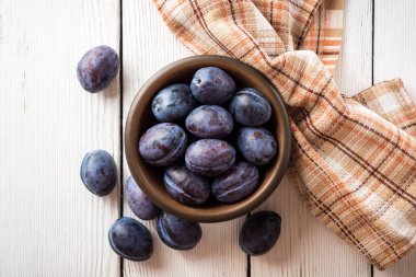 Beyaz ahşap zemin üzerinde seramik kase taze Erik.