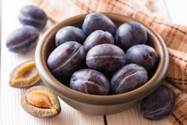 Beyaz ahşap zemin üzerinde seramik kase taze Erik.