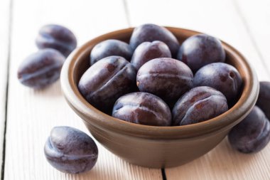 Beyaz ahşap zemin üzerinde seramik kase taze Erik.