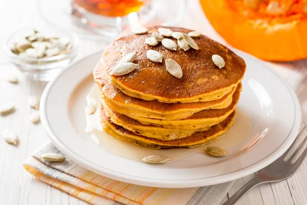 Pumpkin pannkakor med honung och pumpafrön i plattan på vit trä bakgrund. — Stockfoto