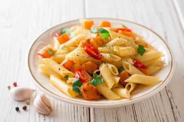 Penne makarna ile kabak, biber ve maydanoz plaka Beyaz ahşap zemin üzerinde