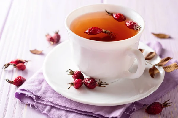 Чашка травяного чая из шиповника на фиолетовом деревянном фоне — стоковое фото