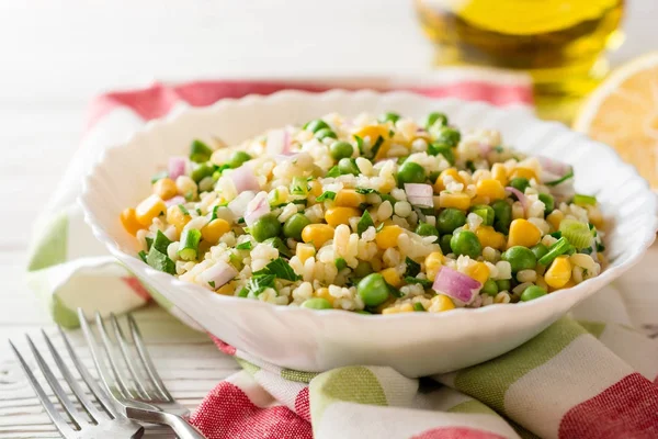 Ensalada con bulgur, guisantes verdes, maíz, cebolla y verduras sobre mesa de madera rústica blanca. Tabbouleh . — Foto de Stock